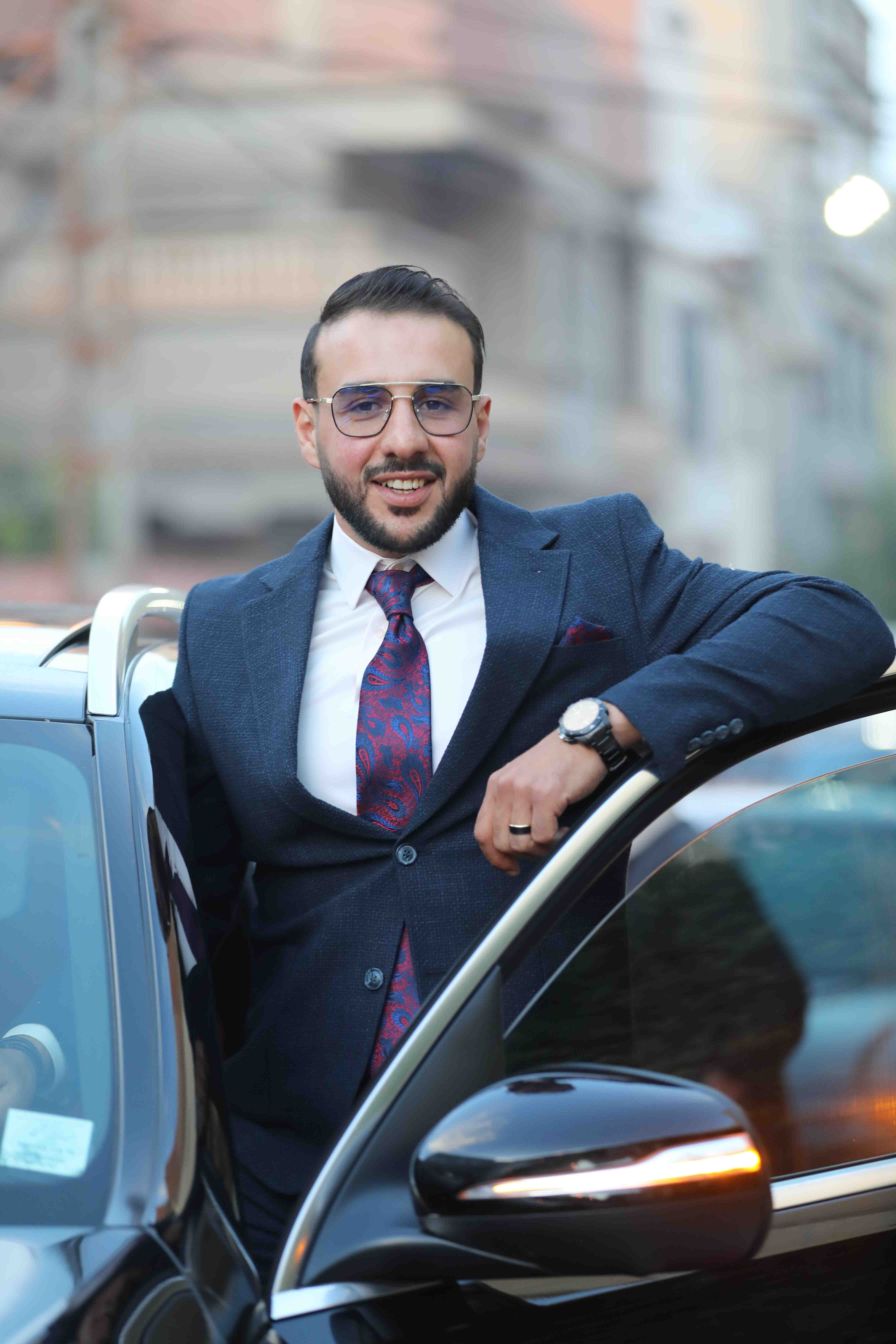 Marié posant devant sa voiture le jour du mariage